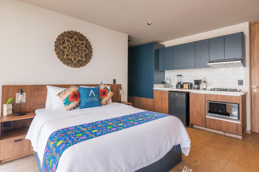 a bedroom with a large bed and a kitchen at Be Local Lofts & Coworking in Mexico City