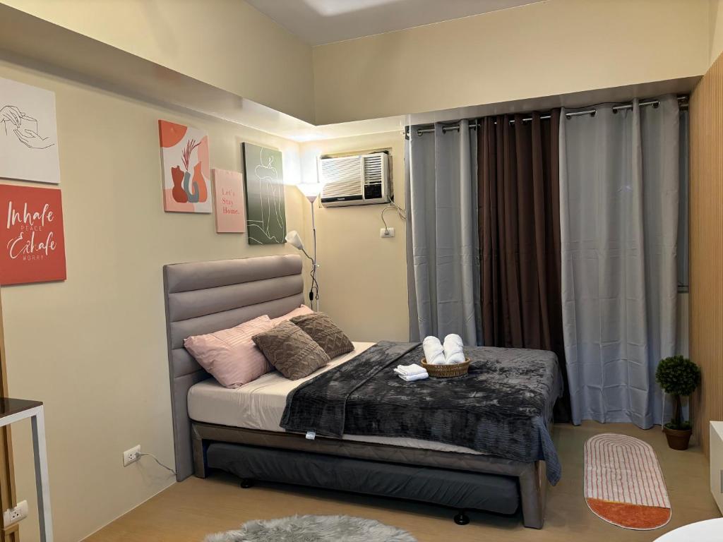 a small bedroom with a bed with pink pillows at Cozy & Minimalist Staycation - Avida Towers with Pool Access in Davao City