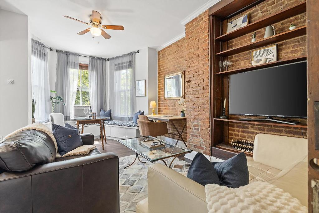 a living room with a brick wall and a flat screen tv at Beautiful 1-BR Flat Nestled Between Dupont & Logan in Washington, D.C.