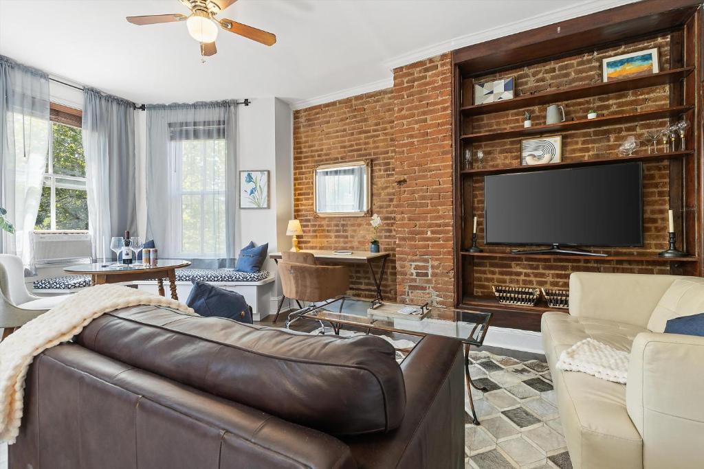 a living room with a couch and a brick wall at Beautiful 1-BR Flat Nestled Between Dupont & Logan in Washington, D.C.