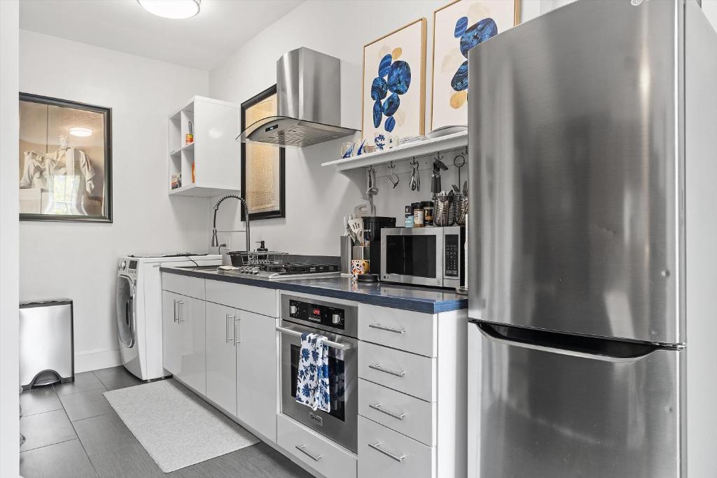 a kitchen with white cabinets and a stainless steel refrigerator at Beautiful 1-BR Flat Nestled Between Dupont & Logan in Washington, D.C.