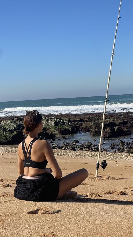 a woman sitting on the beach looking at the ocean at Villa La Falaise in Oualidia