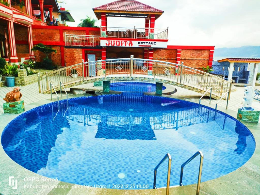 una gran piscina con un puente frente a un edificio en Judita Cottages, en Tuk Tuk