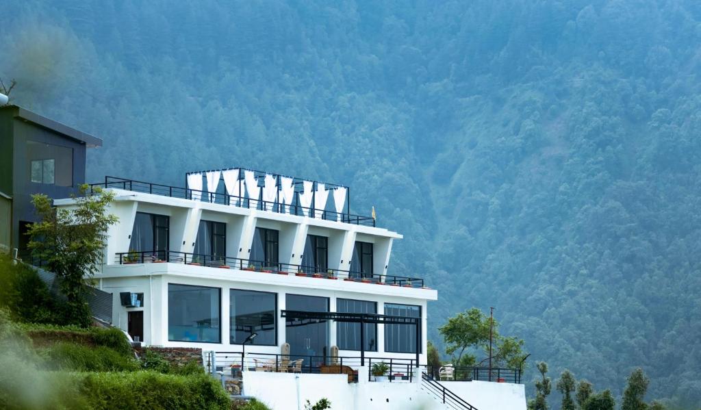 un bâtiment blanc avec une montagne en arrière-plan dans l'établissement Rumuk Boutique Resort - Offbeat escape, à Dhanaulti