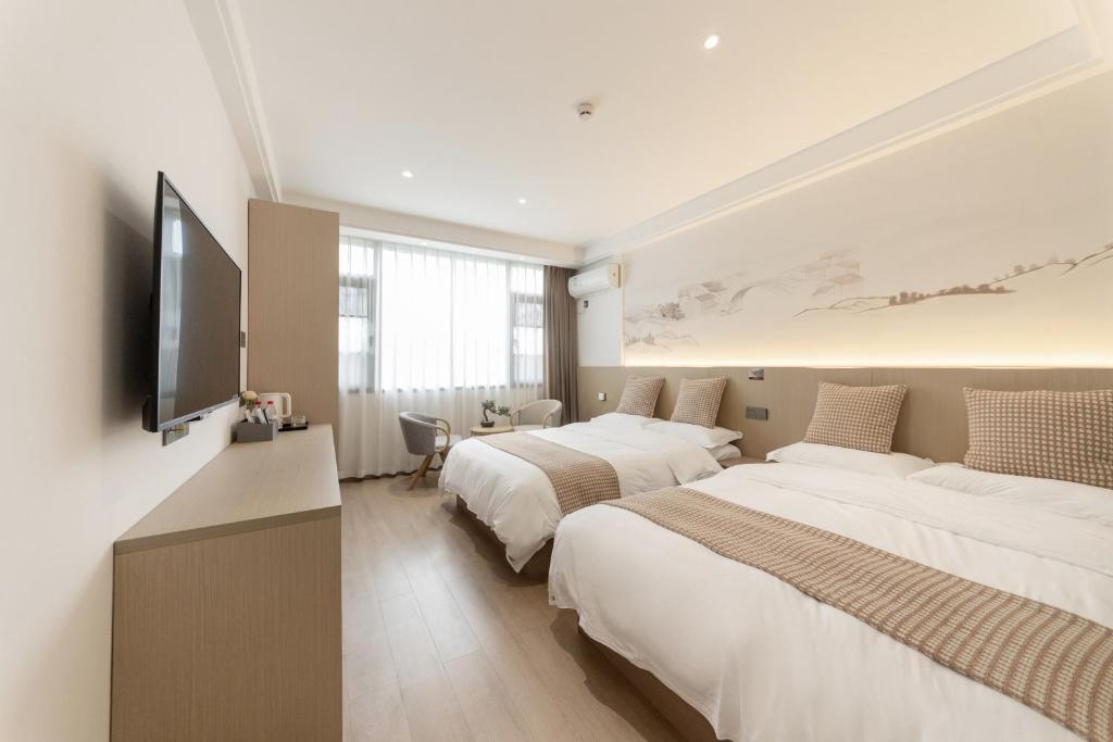 a bedroom with two beds and a flat screen tv at 乌镇闲情逸致精品民宿 in Wujiaqiao