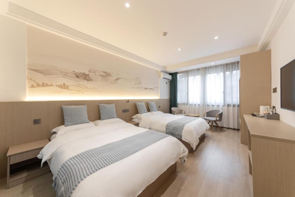 a hotel room with two beds and a television at 乌镇闲情逸致精品民宿 in Wujiaqiao