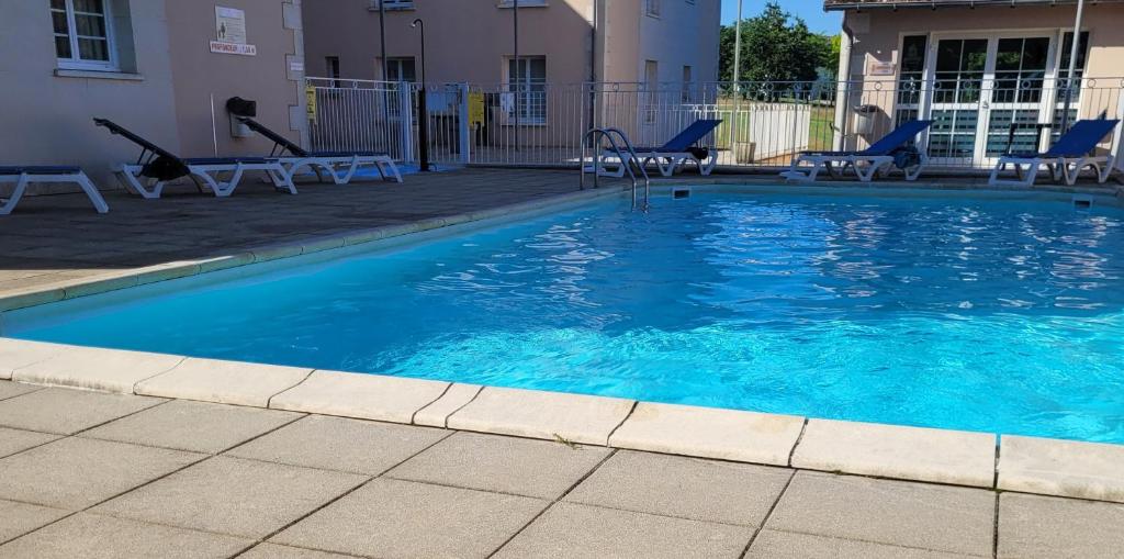une piscine avec de l'eau bleue et des chaises dedans dans l'établissement Studio avec piscine, à La Roche-Posay