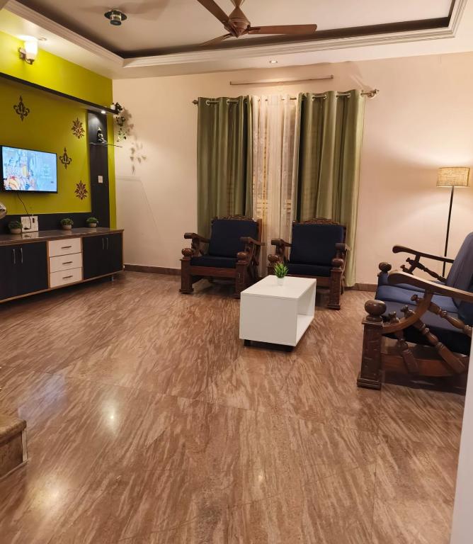 a living room with two chairs and a tv at Flickstays Acacia in Bangalore