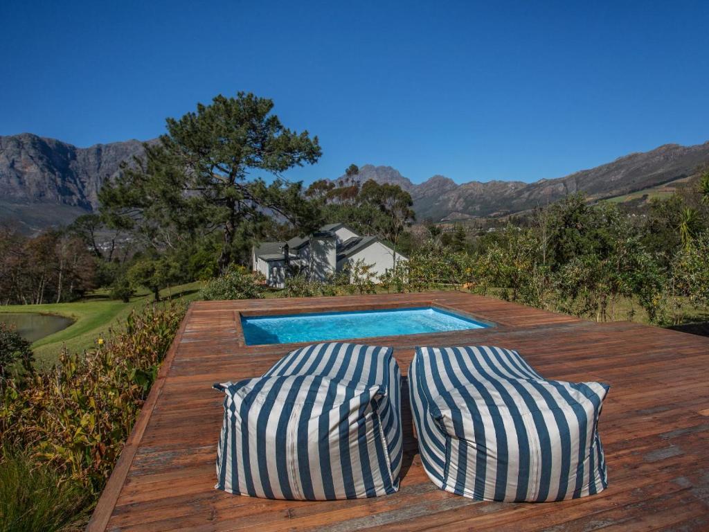 - deux oreillers installés sur une terrasse en bois avec une piscine dans l'établissement Wechmarshof, à Stellenbosch