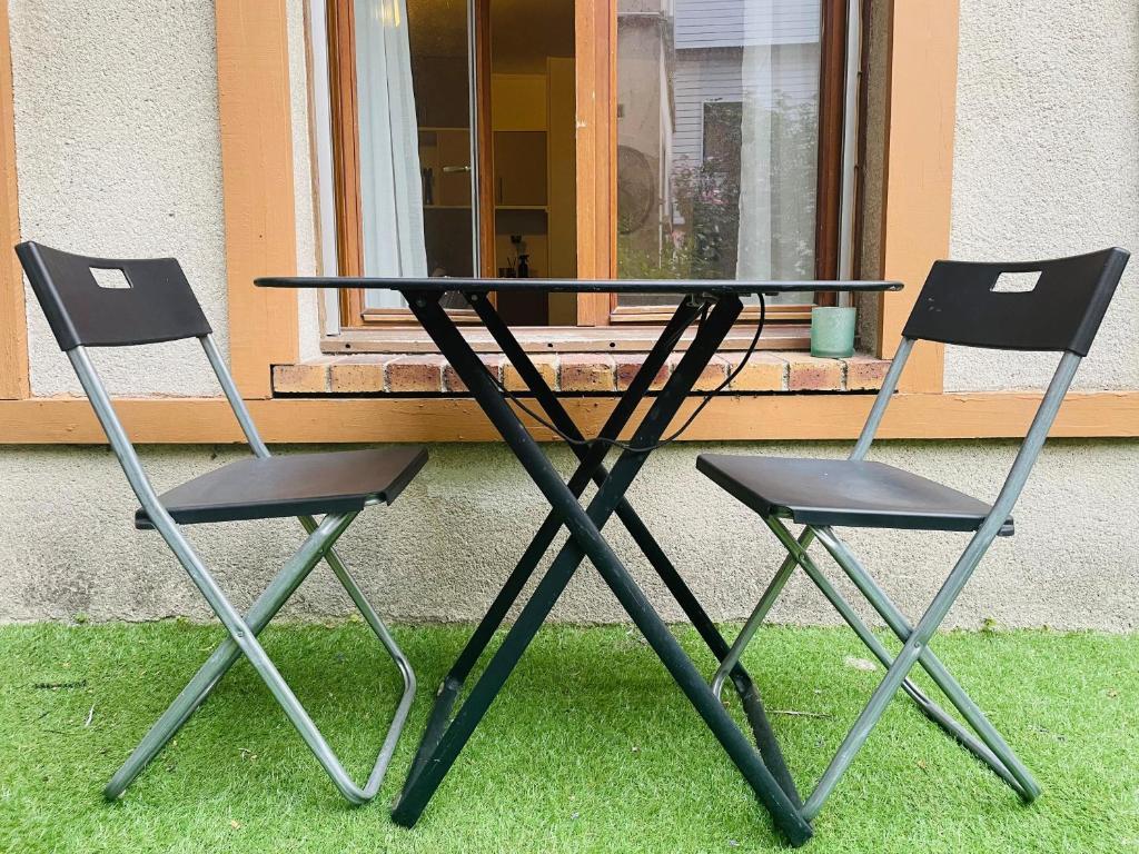 deux chaises et une table devant une fenêtre dans l'établissement Chez Flora ! 344, à Rouen