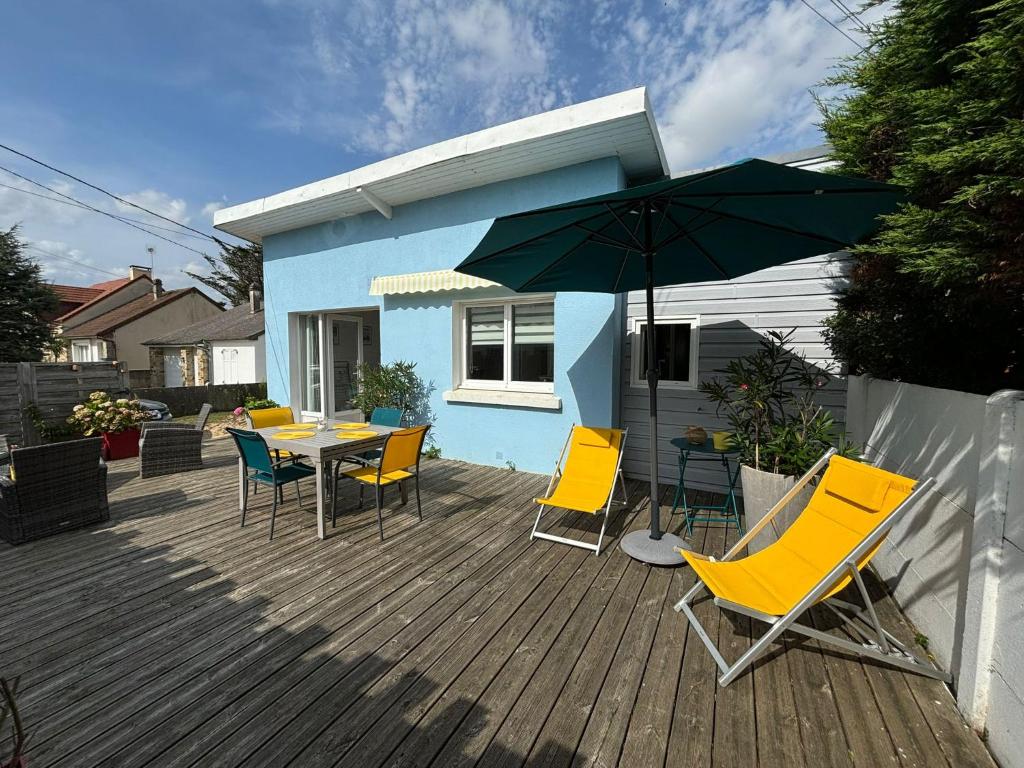 eine Terrasse mit Tisch und Stühlen und einem Sonnenschirm in der Unterkunft C'est une maison bleue, juste à côté de la plage... in Barneville-Carteret