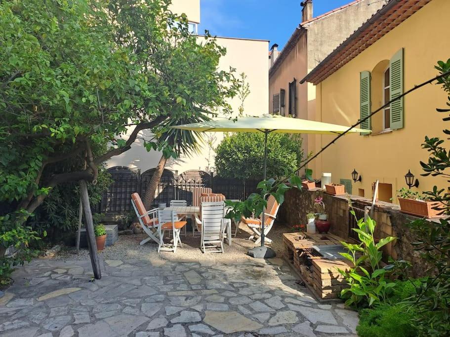 un patio avec une table, des chaises et un parasol dans l'établissement Un rez de jardin en plein centre, à Cannes