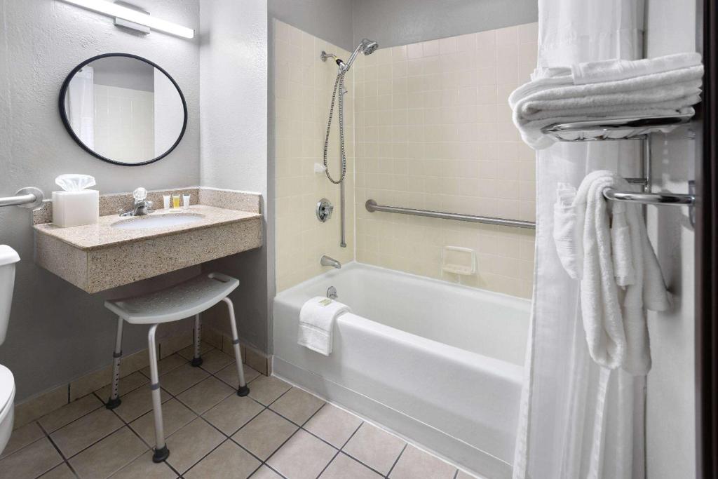 a bathroom with a sink and a tub and a mirror at Super 8 by Wyndham St. Clairsville OH/Wheeling WV Area in Saint Clairsville