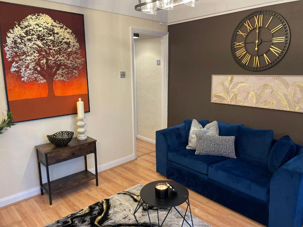 a living room with a blue couch and a clock at Prettide Suite Two-1 free Parking in Gillingham