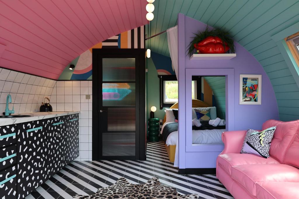 a room with a pink couch and a bed at Ammonite Glamping Pod & Hot Tub in Hungerton