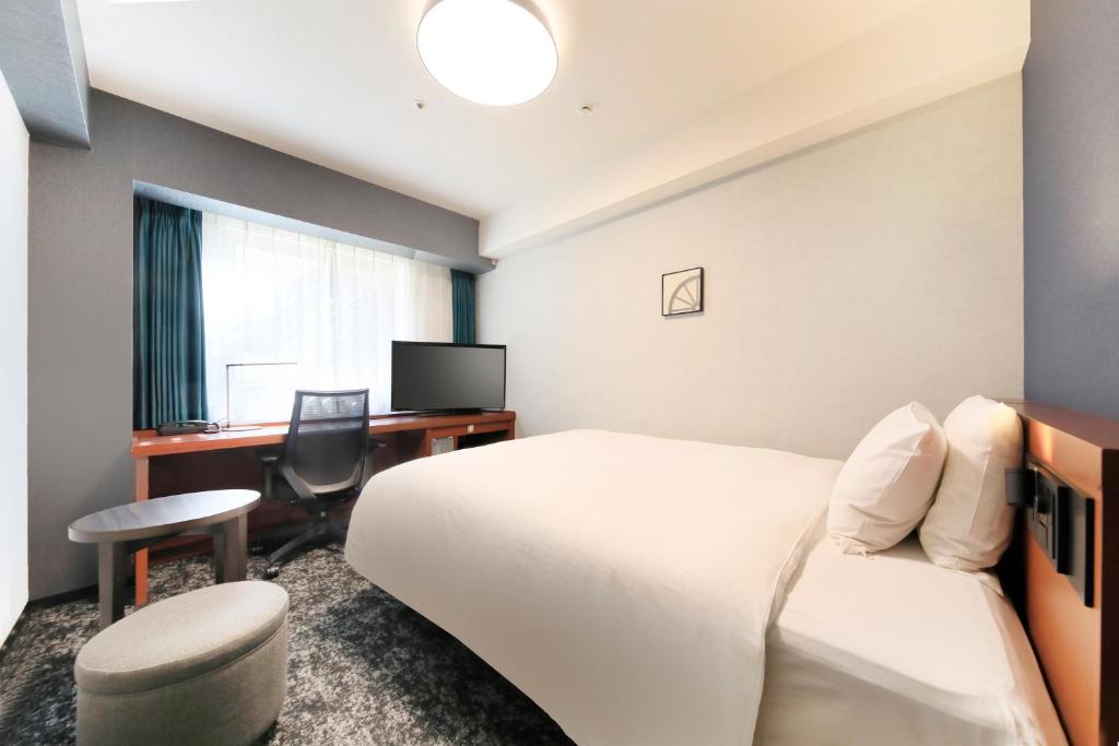 a hotel room with a bed and a desk at Richmond Hotel Yokohama-Bashamichi in Yokohama
