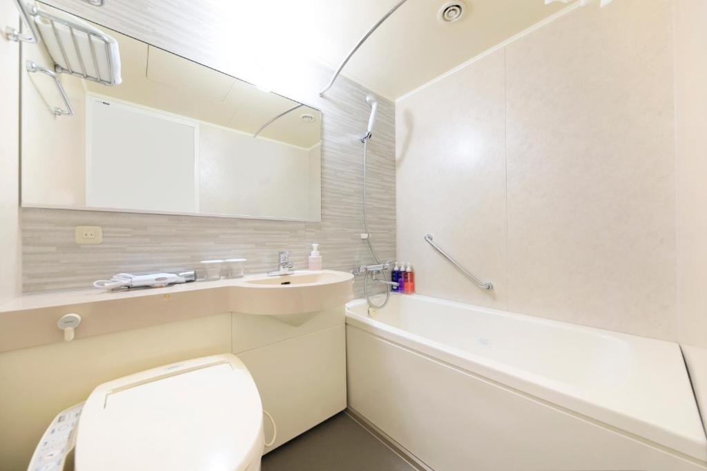 a white bathroom with a toilet and a sink at Richmond Hotel Yokohama-Bashamichi in Yokohama