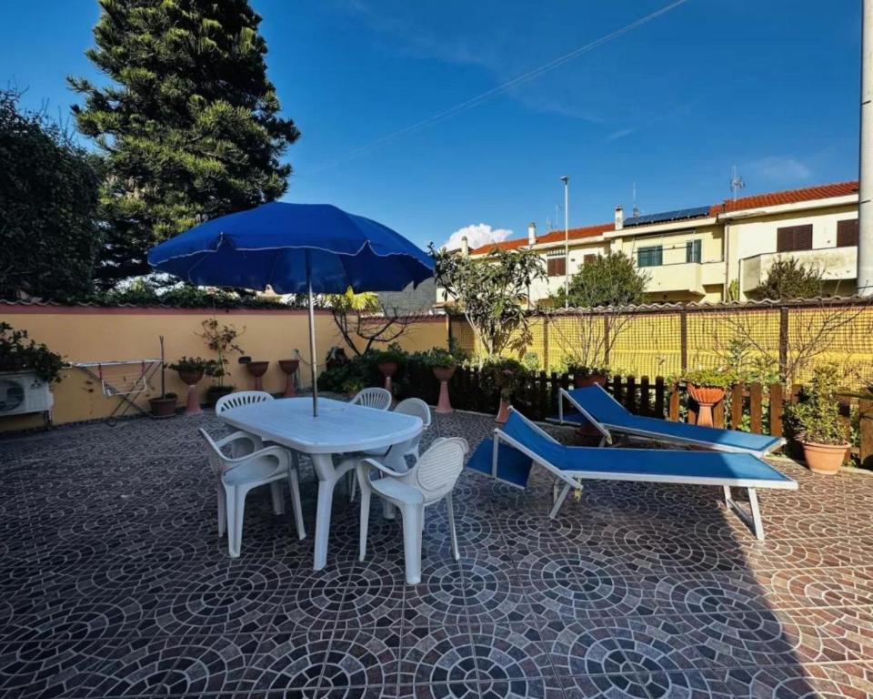 una mesa, sillas y una sombrilla en el patio en Romano House, en Fiumicino