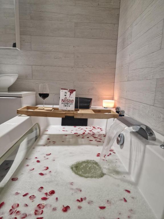 a bathtub filled with blood with a table and a glass of wine at Apartament w Centrum z wanną z hydromasażem in Kętrzyn