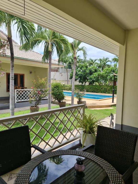 Un balcón con mesa y sillas y palmeras. en 1 Bedroom House With Pool In Central Location, en Hua Hin