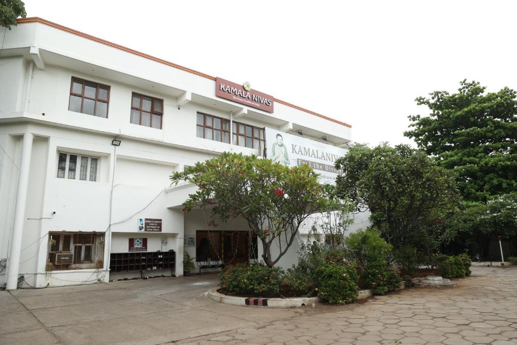 a white building with trees in front of it at Sri Kamalanivas in Vellore