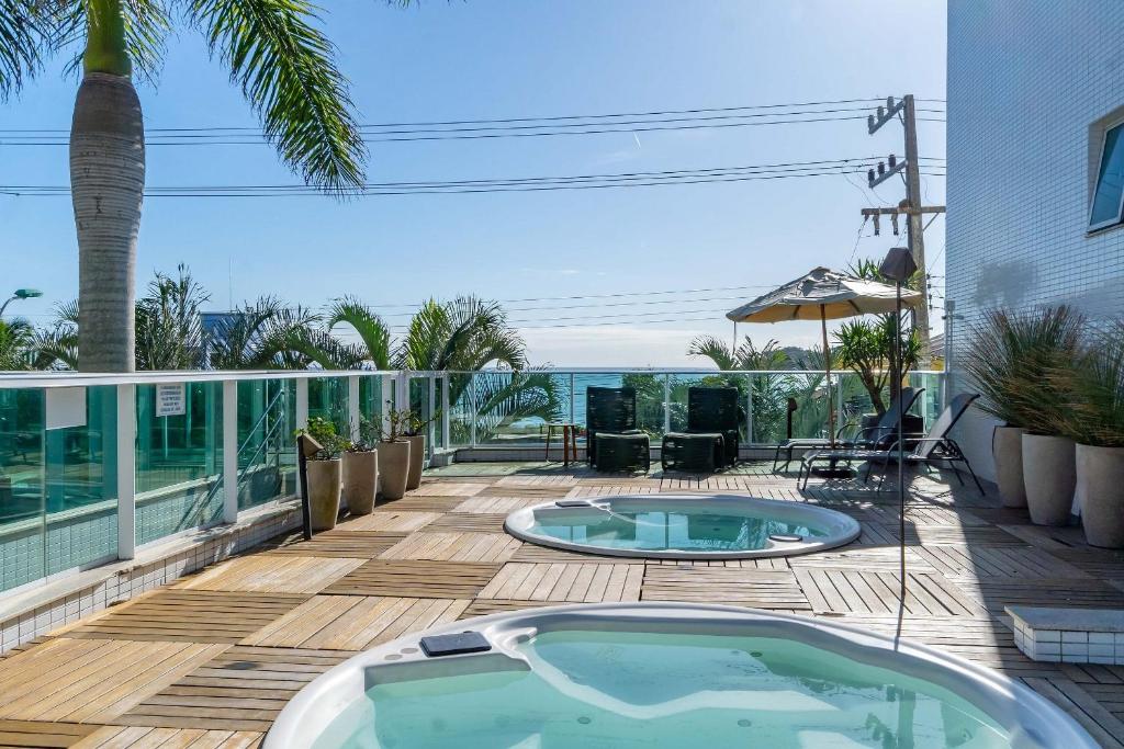 a hot tub on a deck with a view of the ocean at Apartamento em Condomínio com Piscina e Jacuzzi - Boulevard Bombinhas in Bombinhas