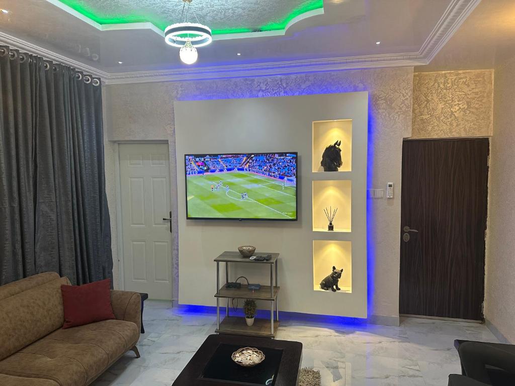 a living room with a couch and a tv on a wall at Lesley and Lindsey luxurious short let in Gwarinpa