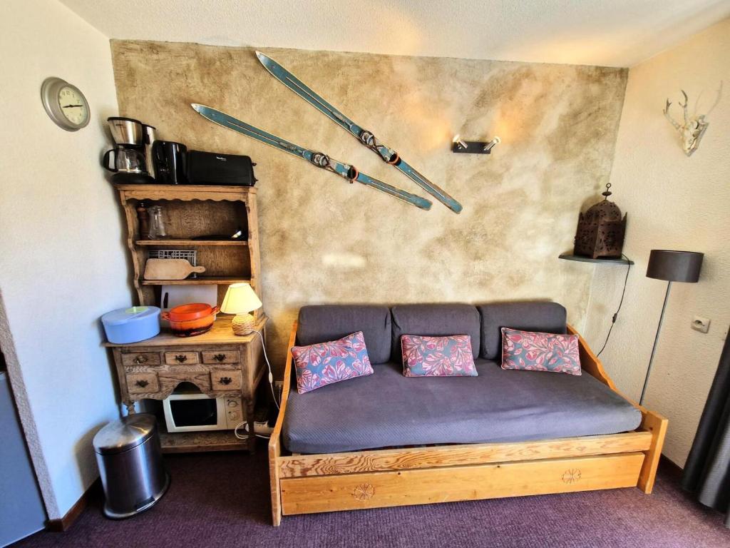 Cette chambre dispose d'un canapé avec des skis sur le mur. dans l'établissement Chalet Club - Studio 17 m² MAE-2985, à Modane