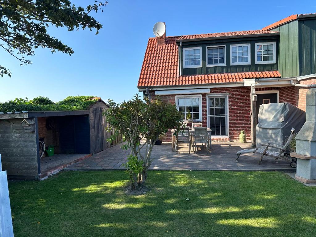een huis met een patio en een stoel in de tuin bij "Huus ant Diek", Ferienhaus mit Maisonette Wohnung in Deichnähe, Nähe Norddeich in Norden