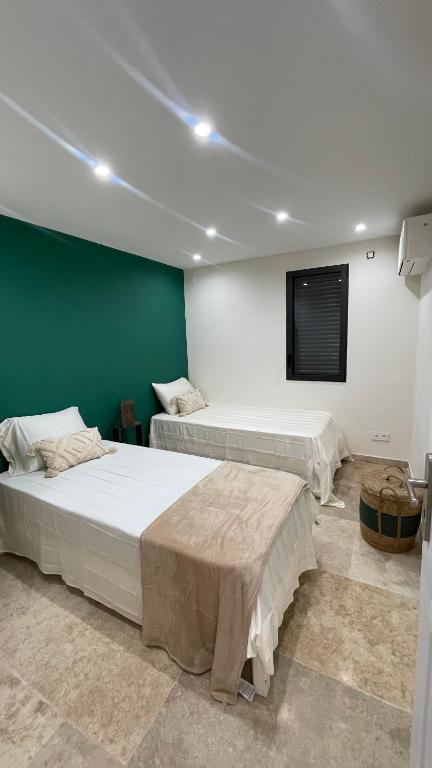 - une chambre avec 2 lits et un mur vert dans l'établissement Villa piscine, à Roquefort-les-Pins