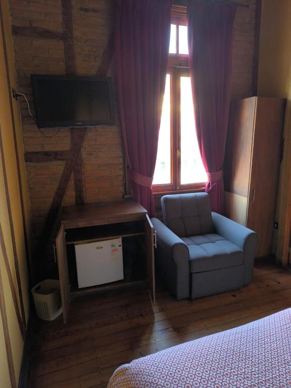 a room with a couch and a tv and a window at Hotel Reina Victoria Valparaíso in Valparaíso