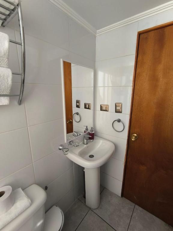 a white bathroom with a sink and a toilet at Hotel Reina Victoria Valparaíso in Valparaíso