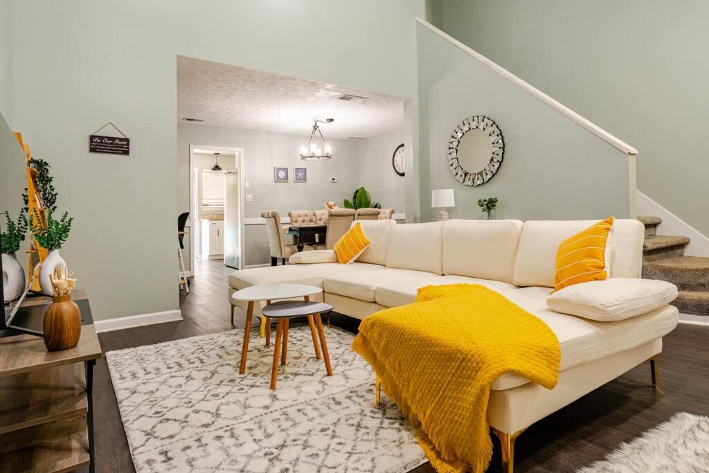 a living room with a white couch and a yellow blanket at Cozy home with BBQ grill, Firepit, Basketball and Foosball in Alpharetta