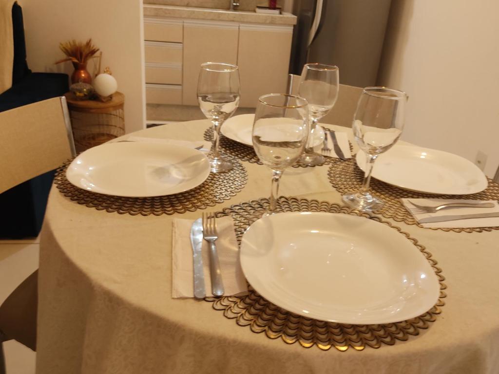 een tafel met witte borden en wijnglazen erop bij Praia canavieiras in Florianópolis