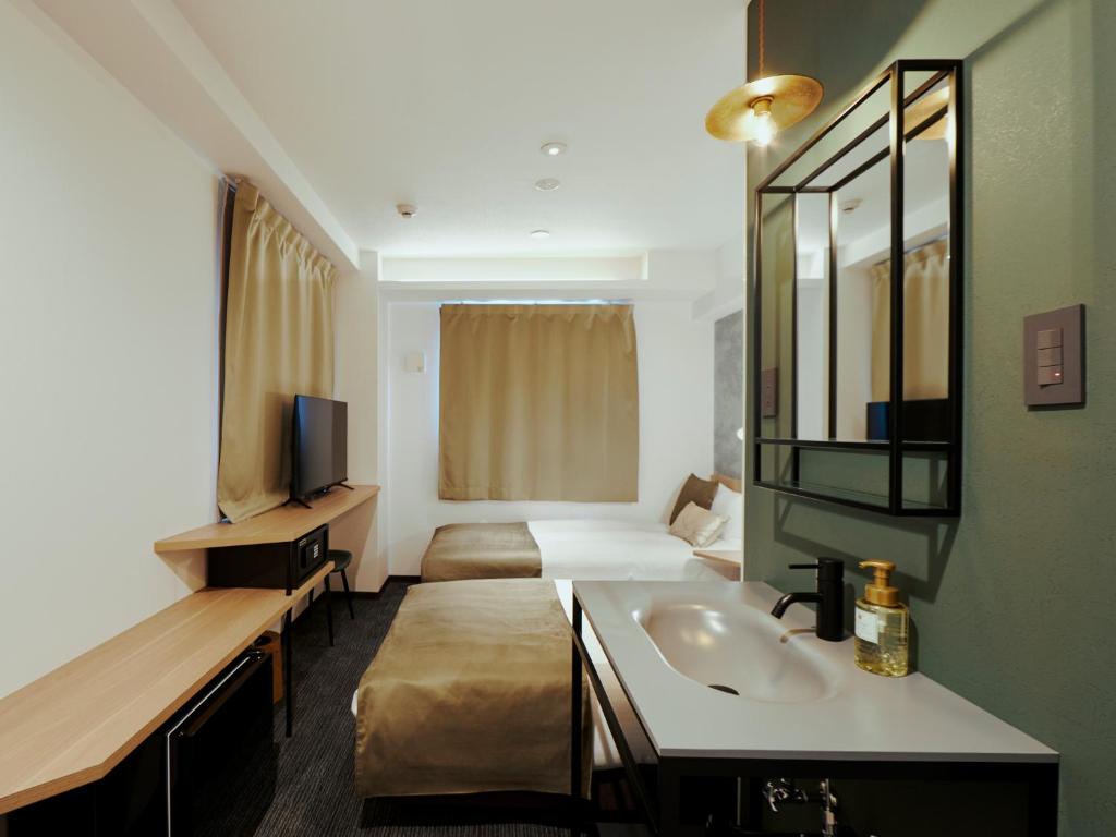 大阪市にあるR Hotel Namba Daikokuchoのシンクとベッドが備わるホテルルームです。