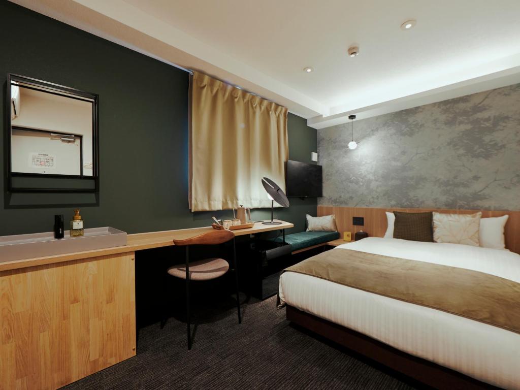 大阪市にあるR Hotel Namba Daikokuchoのベッドと机があるホテルの部屋