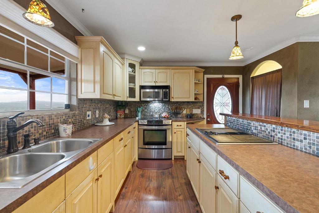 a kitchen with a sink and a stove top oven at Entire 2br 2ba hilltop view home Sleeps 8 pets 4 acres Jacuzzi Central AC Kingbeds Free Wifi-Parking Kitchen WasherDryer Starry Terrace Two Sunset Dining Patios Grill Stovetop Oven Fridge OnsiteWoodedHiking Wildlife CoveredPatio4pets & Birds Singing! in Marble Falls