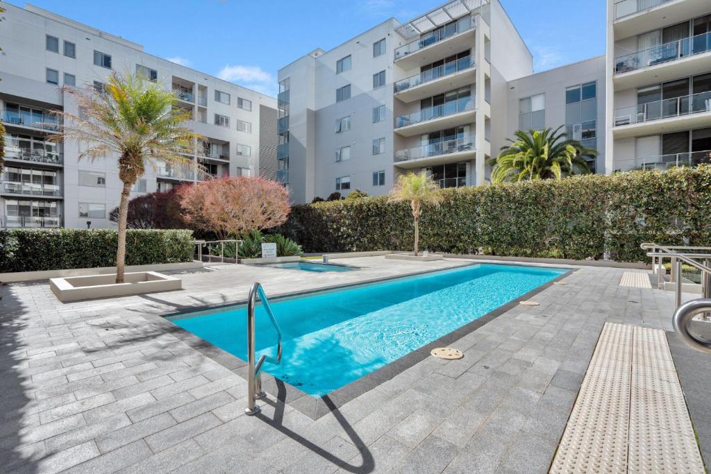 a swimming pool in a apartment with buildings in the background at Modern 1-Bed Unit with Pool Views and Balcony in Canberra