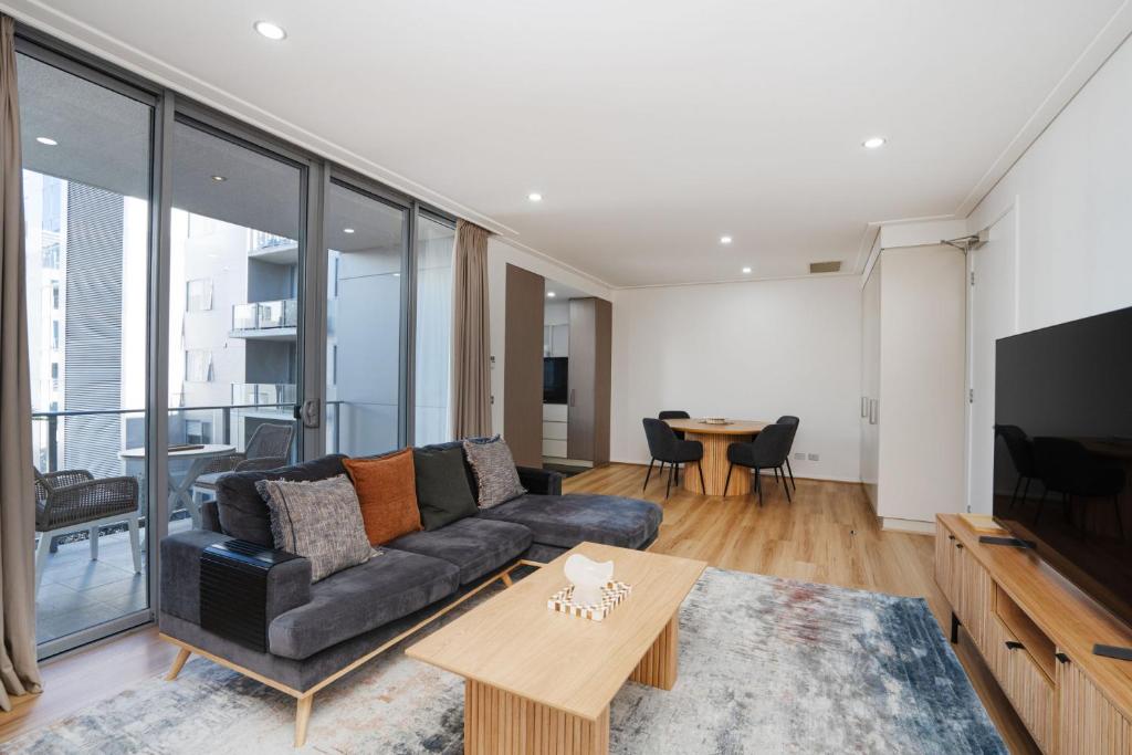 a living room with a couch and a table at Modern 1-Bed Unit with Pool Views and Balcony in Canberra