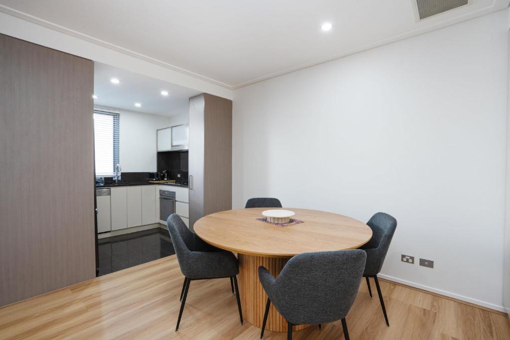 a kitchen and dining room with a wooden table and chairs at Modern 1-Bed Unit with Pool Views and Balcony in Canberra