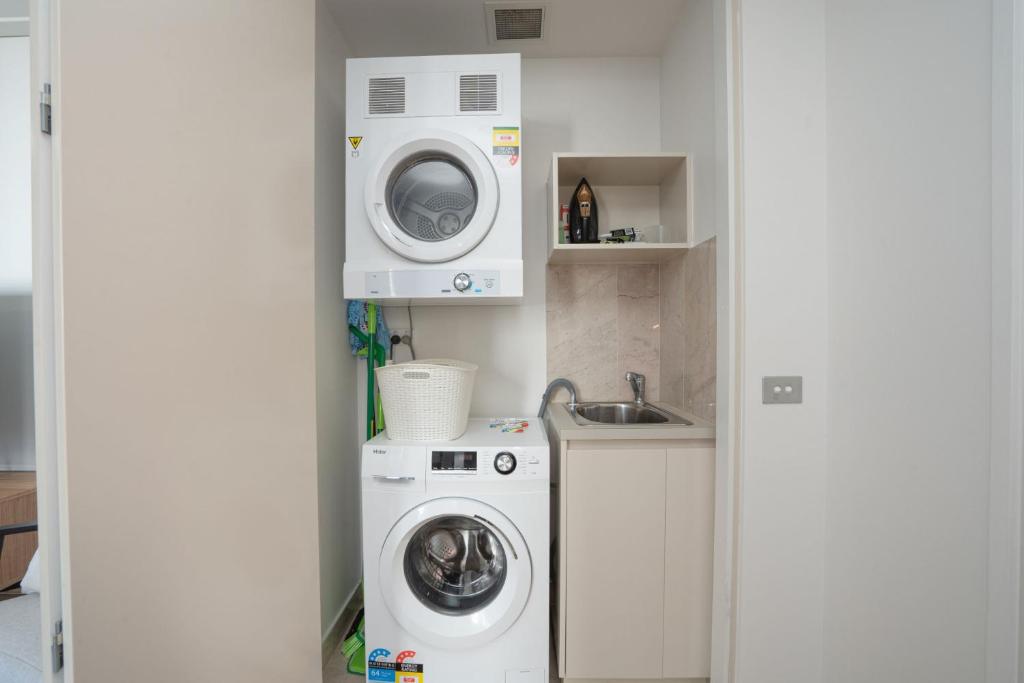 a laundry room with a washing machine and a washer at Modern 1-Bed Unit with Pool Views and Balcony in Canberra