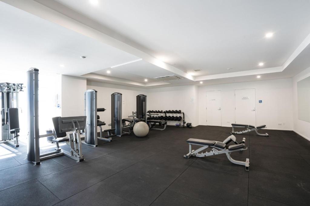 a gym with several treadmills and machines in a room at Modern 1-Bed Unit with Pool Views and Balcony in Canberra