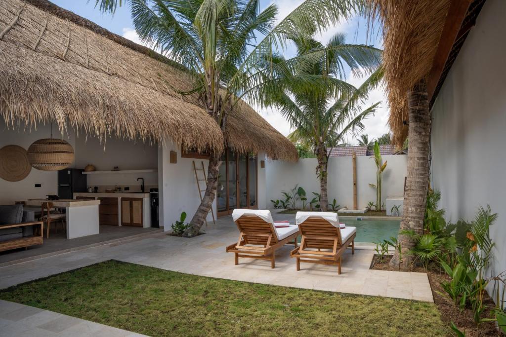 a patio with chairs and a table and a pool at Flora Villa Priv Pool By Yemaya in Kuta Lombok