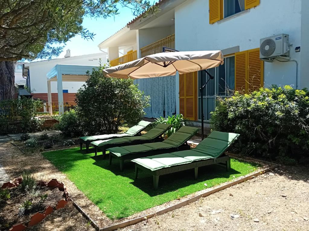quattro sedie verdi e un ombrellone su un prato di Villa Gialla IUN Q5511 a Pula