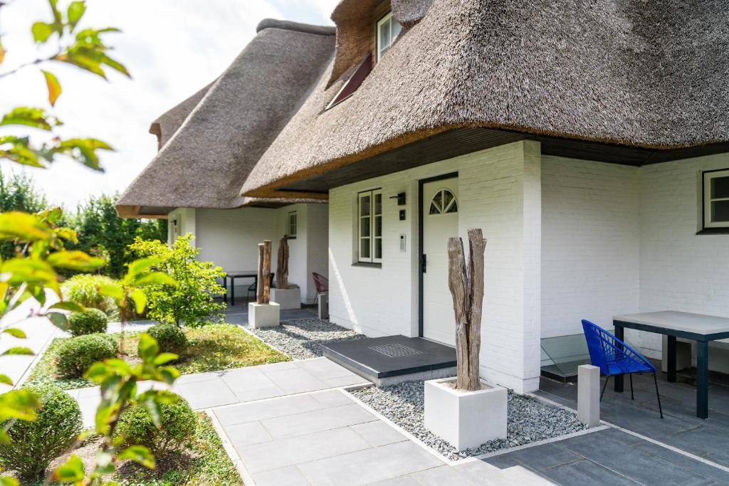 a cottage with a thatched roof and a patio at Beach Lodge Beach Lodge Appartement 1 in Böhl