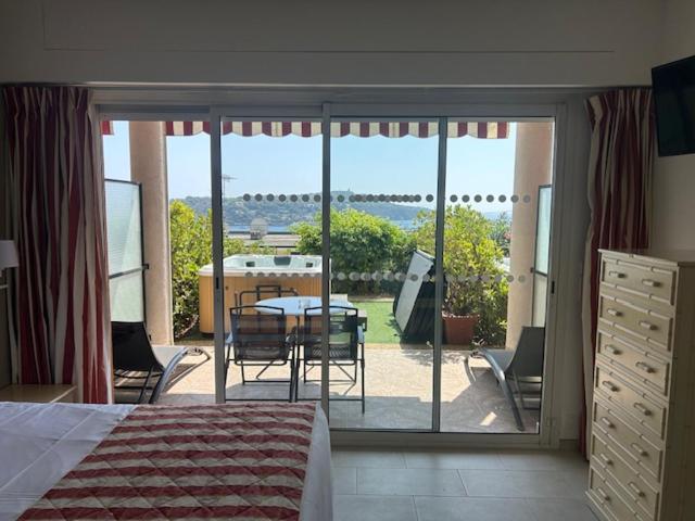a bedroom with a view of a patio with a table and chairs at Hôtel La Flore in Villefranche-sur-Mer
