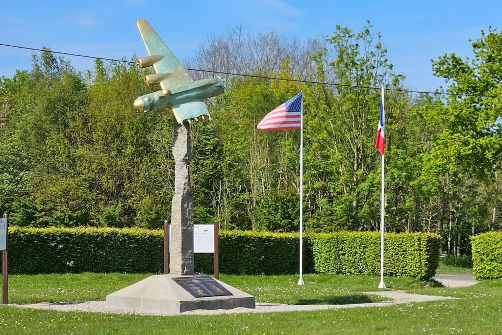 a statue of an airplane on display next to two flags at La Maison Bricquebetaise in Bricquebec