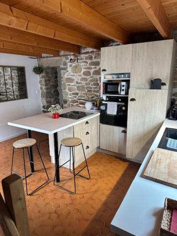 - une cuisine avec une table et deux tabourets dans l'établissement jolie maisonnette proche plage et activités nautiques, à Ploudalmézeau