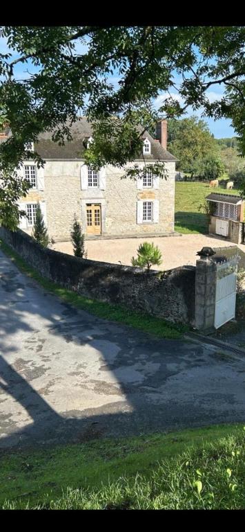 une grande maison avec un mur de pierre devant elle dans l'établissement Maison Paisible au coeur des Pyrénées, à Igon