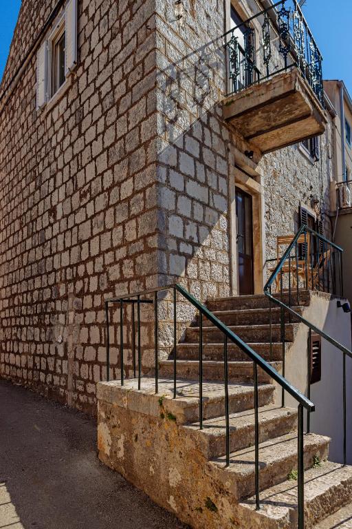 a brick building with stairs and a balcony at Old Charming House in Lastovo